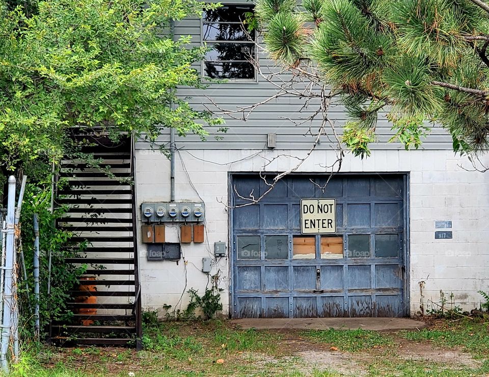 A run down urban garage with an ominous warning sign