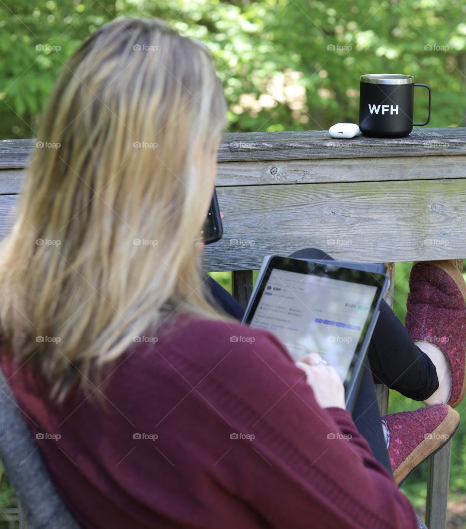 Woman Outdoors Checking stats online on Gen 7 iPad with AirPod 2 and “Work From Home” Coffee Cup