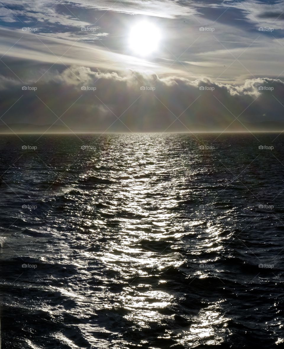 Sun shines beams of lights on dark ocean top