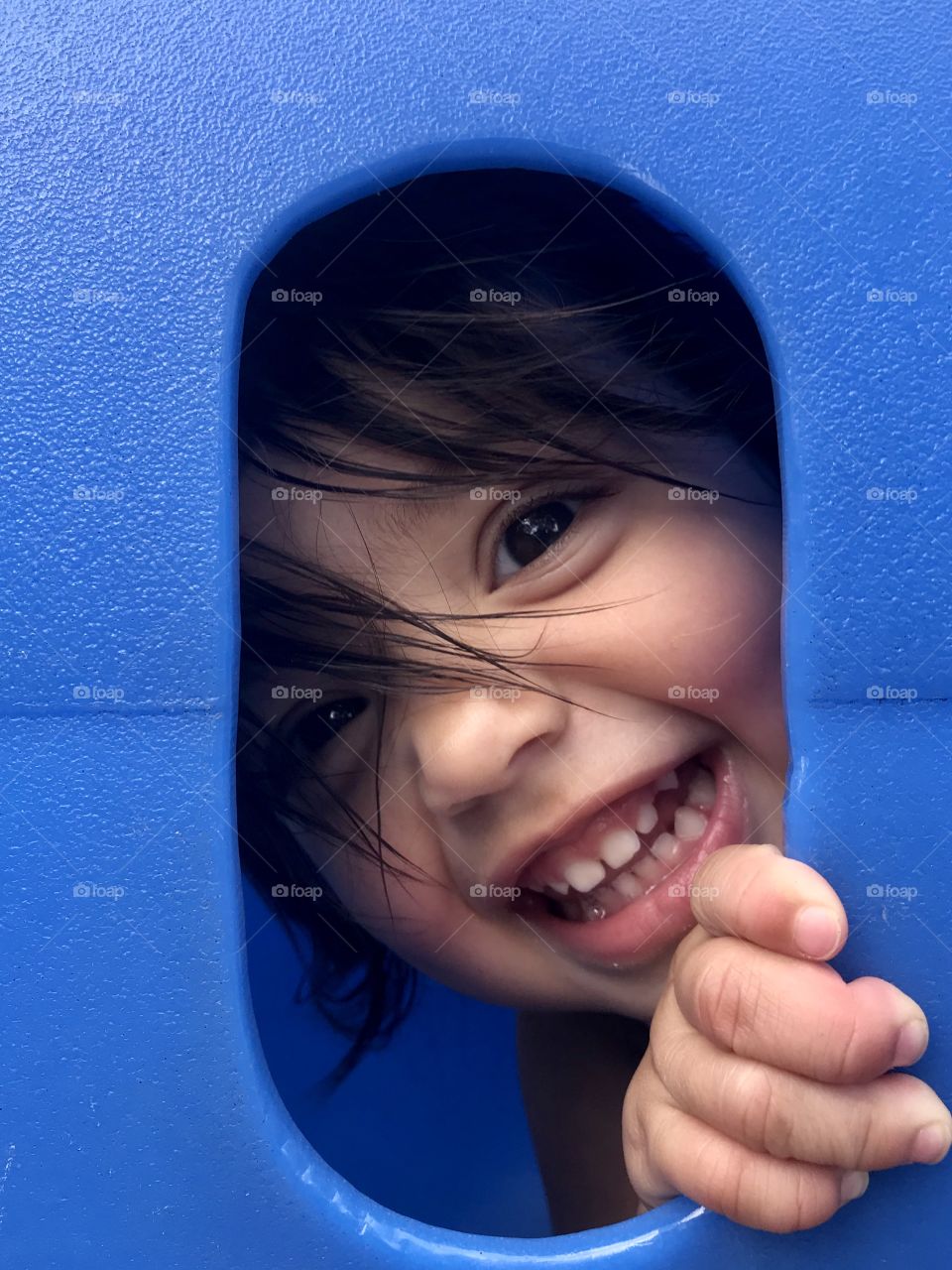 Baby girl looking through a playground tunnel