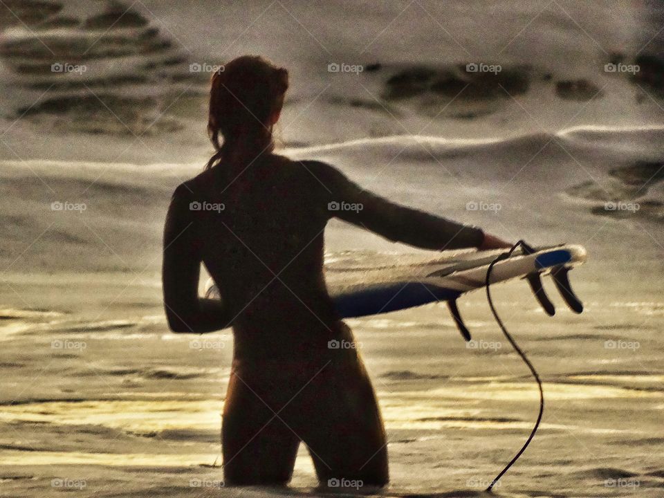 Female surfer entering the waves near Mavericks in Half Moon Bay, California

