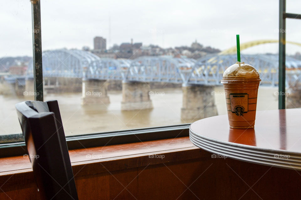 Starbucks frappachino cup on a table at a Barnes and Noble cafe with a view of a river, bridge and city in the background