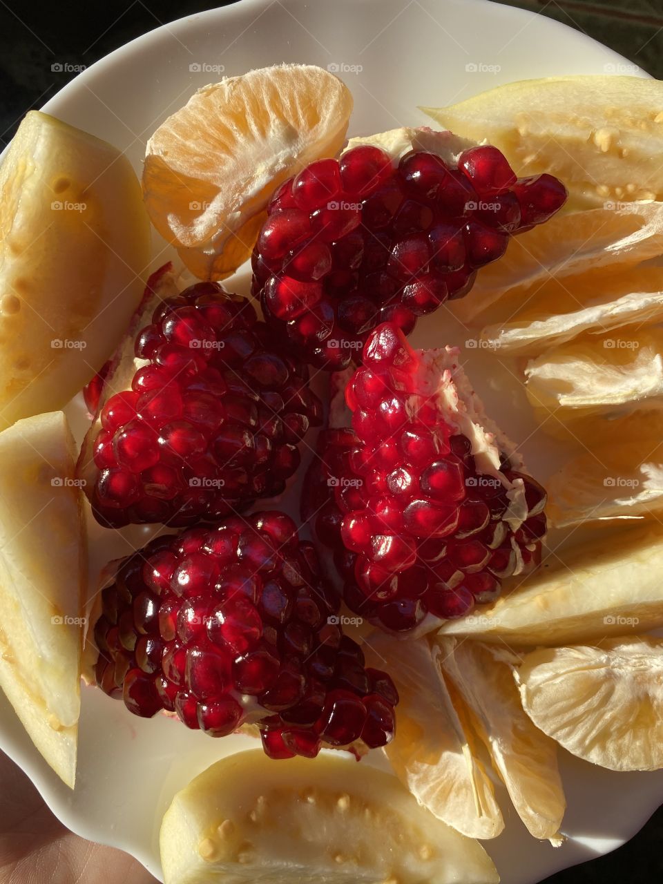 Pomegranate and other fruit on a white plate