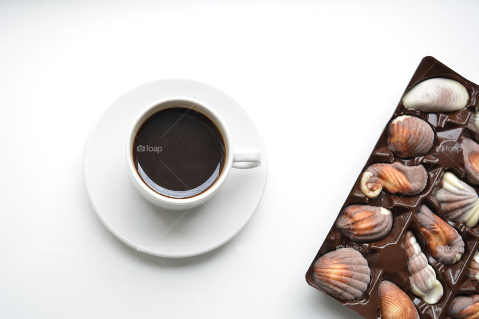 coffee mug and chocolate candies on a white background top view