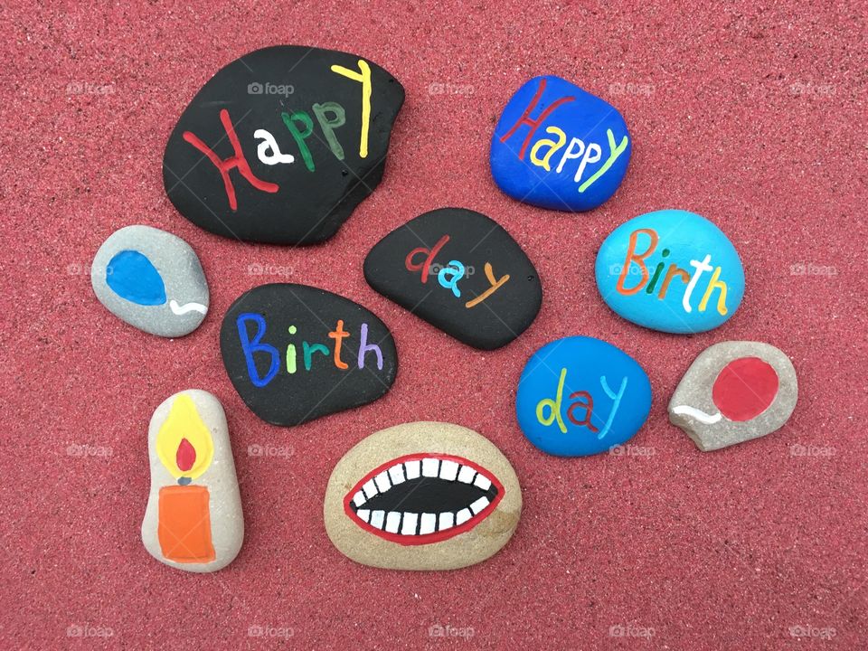 Double Happy Birthday message on colored stones on red sand 