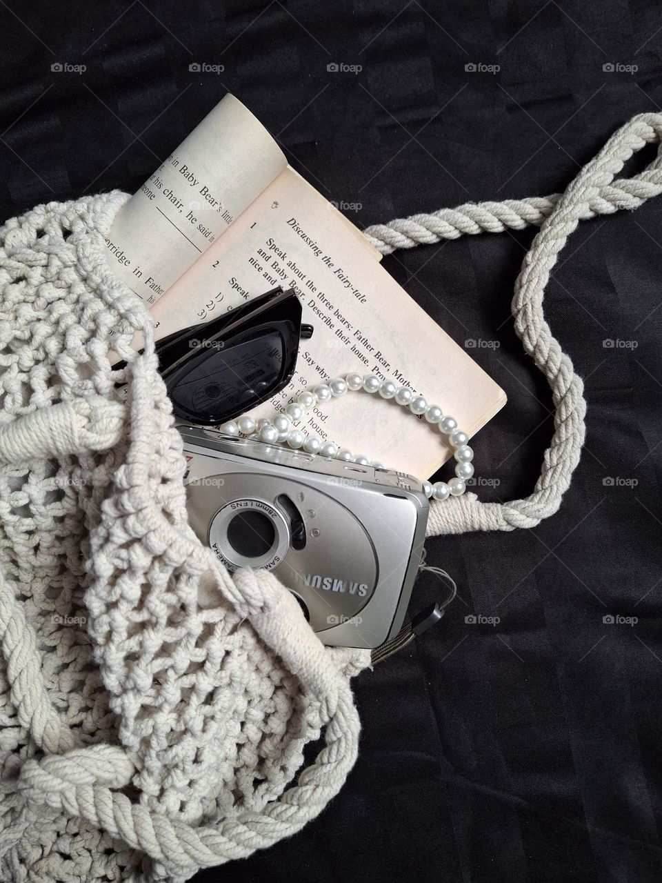 old book vintage glasses and film camera folded in a woven bag