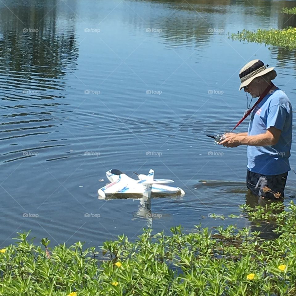 Man in water lake river marsh operating a remote control boat watercraft drone