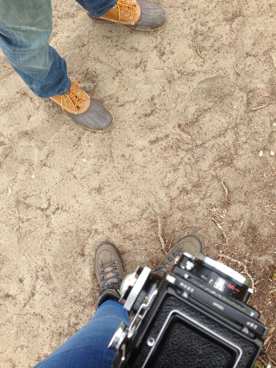 Two peoples feet in sand with vintage camera 