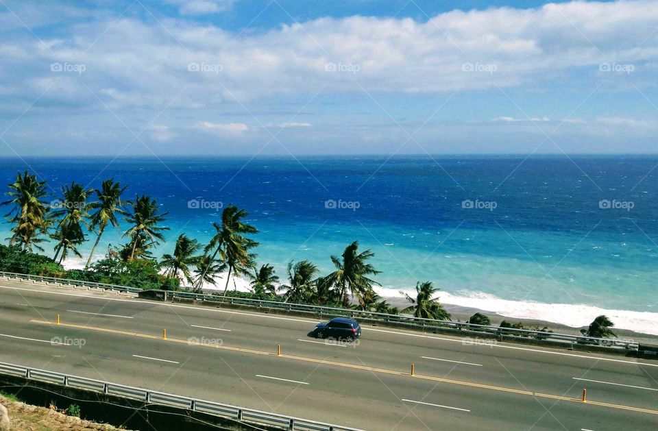 Day and night: beautiful Pacific Ocean water colors and beach, coconut trees, coastal road. it is a beautiful day.