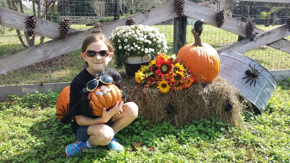 Little smiling girl holding pumpkin