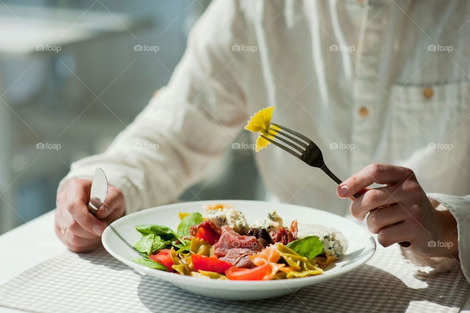 close-up of a young man eating a salad in a light kitchen