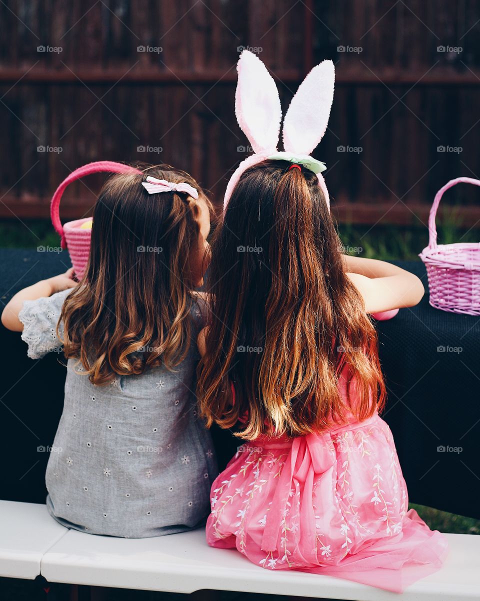 The closeness of cousins on Easter while one wears bunny ears while they count their candy