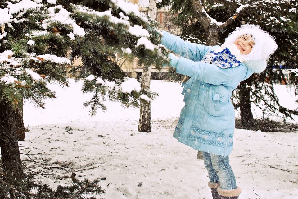 girl pulling a spruce brunch with snow