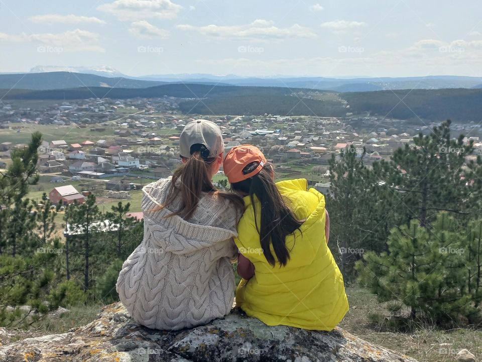 two sisters sitting on a mountain rock.