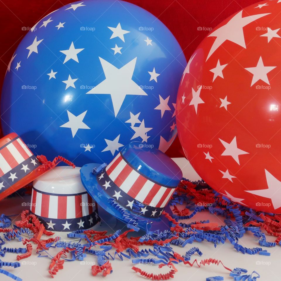 Tiny party hats in red, white, and blue with the Stars and Stripes for hat bands on a table with confetti. 