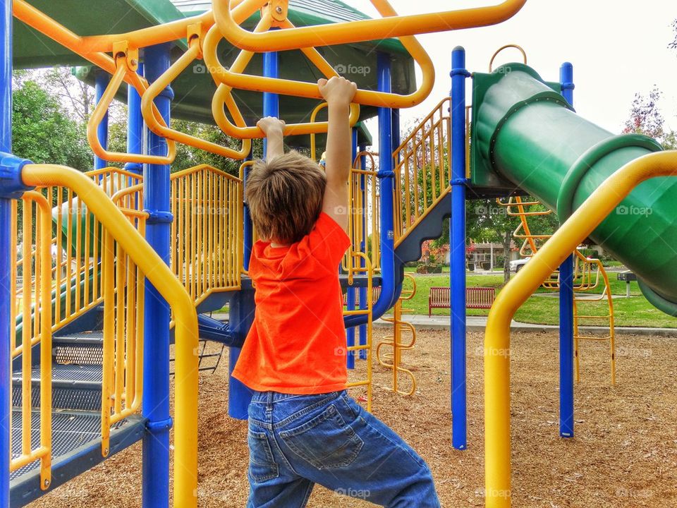 Boy Playing On Jungle Gym. Child Swinging On Monkeybars
