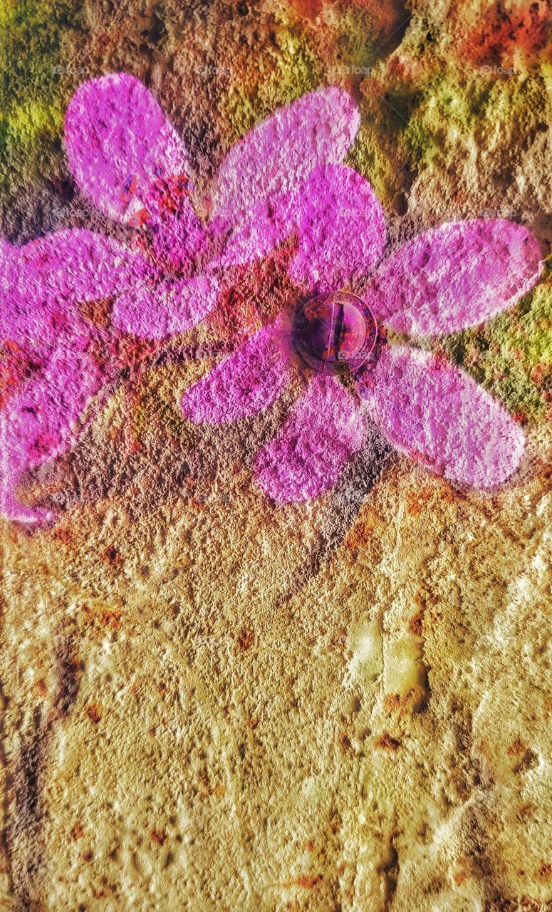 a white pimply and rough stucco wall with bright graffiti with purple flowers applied on it. a screw is screwed into one of the flowers.