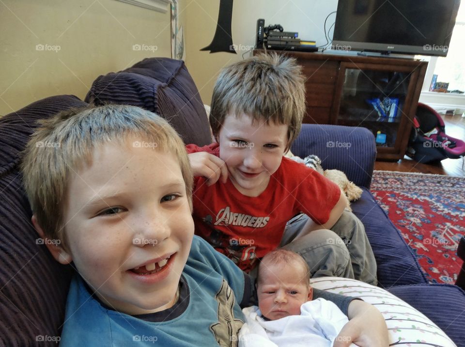 Brothers Holding Their Newborn Baby Sister

