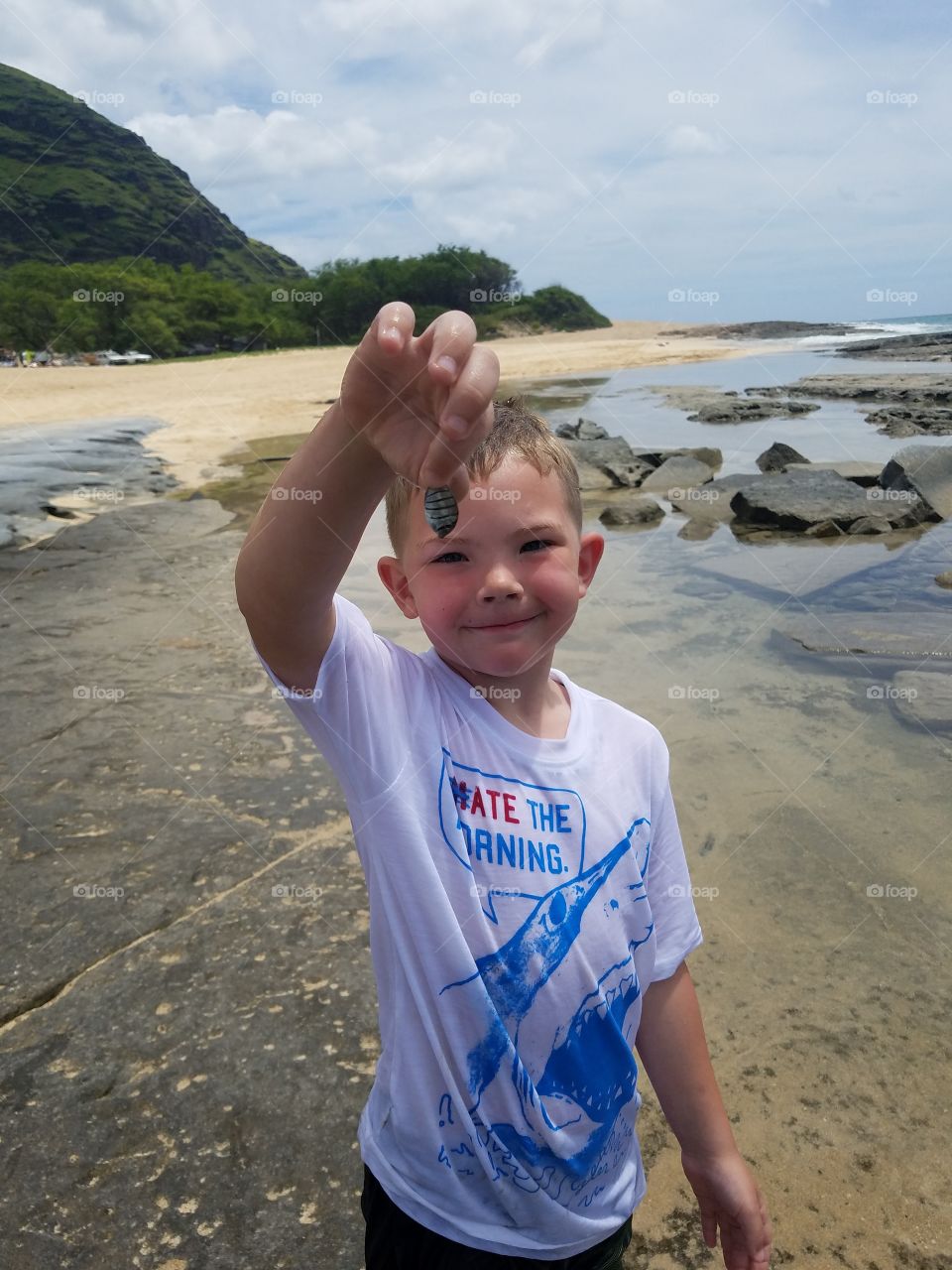 Little boy holds up fish he found in tidal pools.