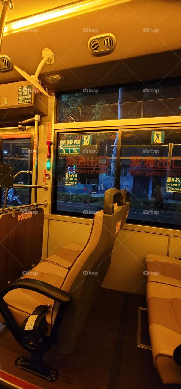 A retro-style bus with a warm yellow light interior.Safety equipment window breakers.bus seat