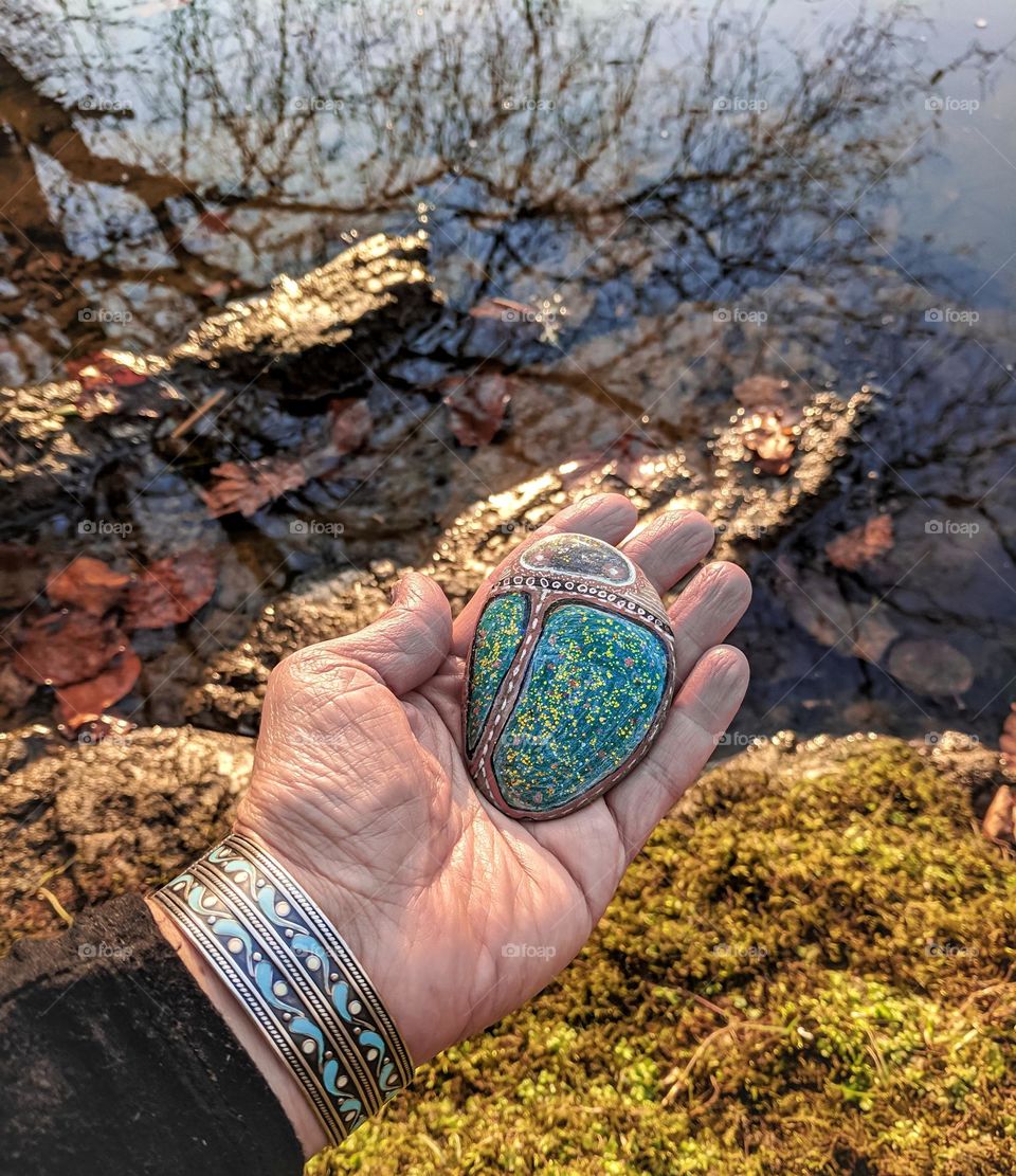 Hand holding painted pebble bug