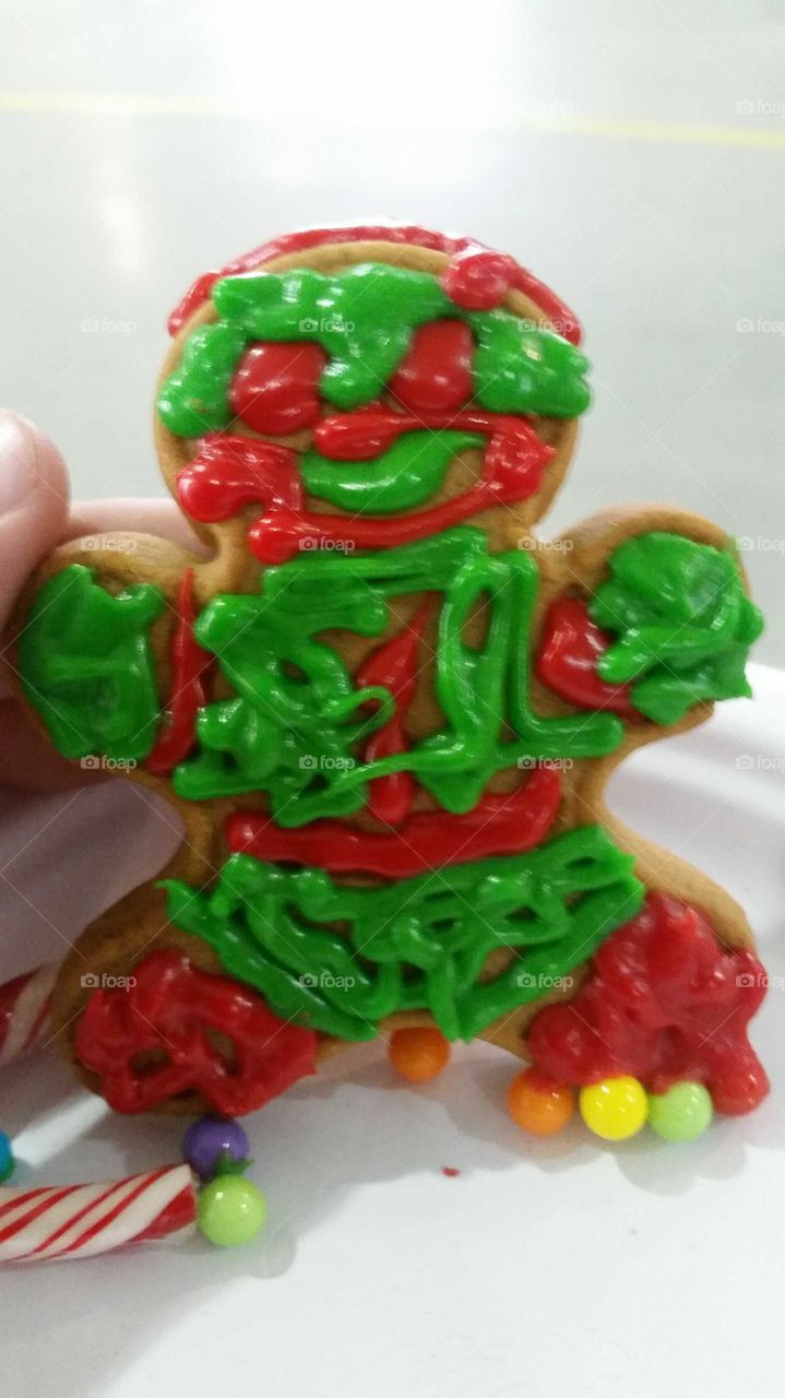 a handmade gingerbread man decorated in green and red frosting