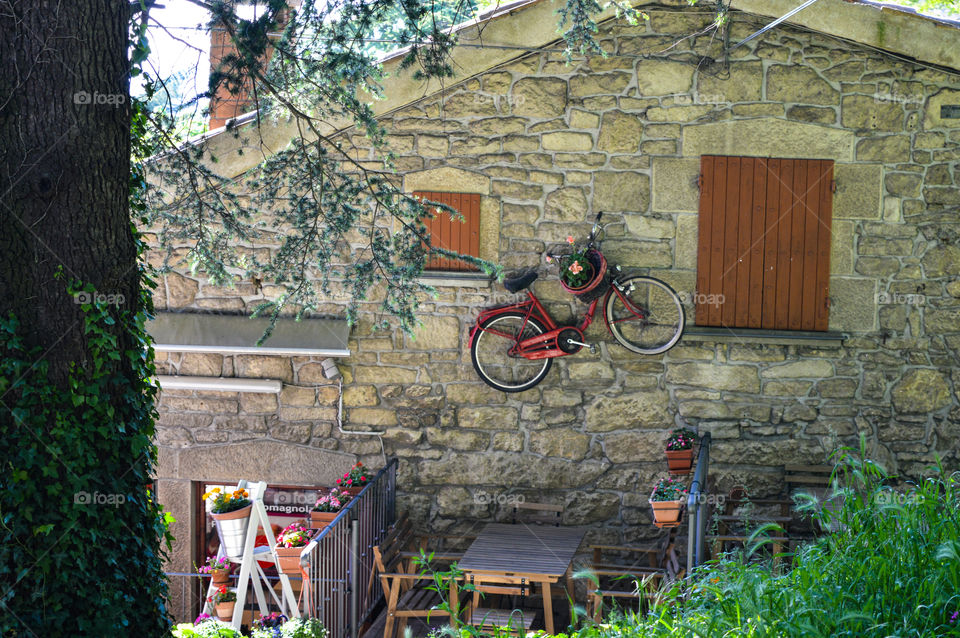 una bici rossa appesa alle mura di una casa rustica.