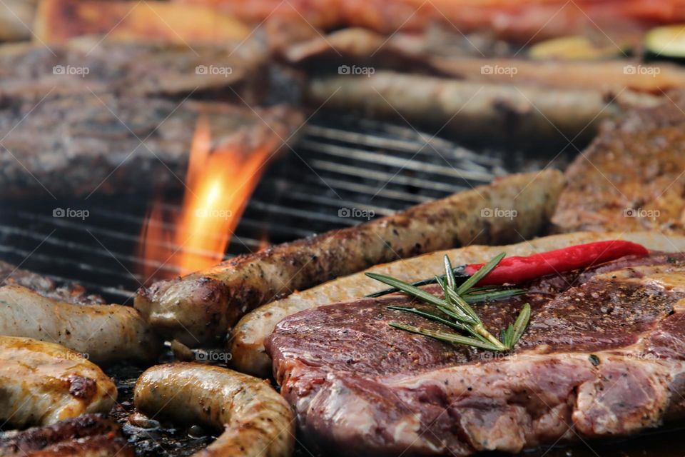 Meat with spices and sausages lie on the grate over fire for the first barbecue in spring