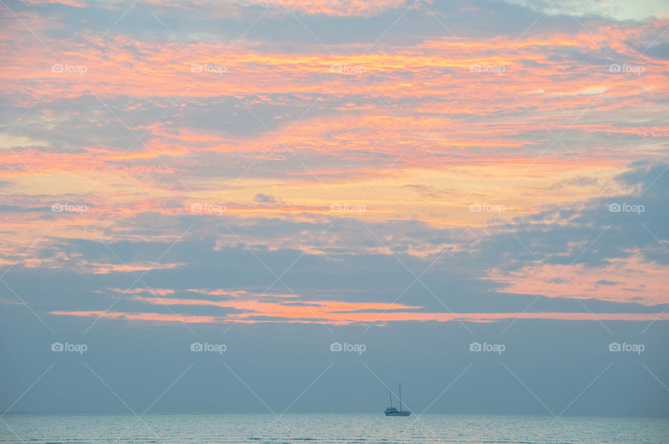 Boat sailing through pink sunset in Darwin, Australia