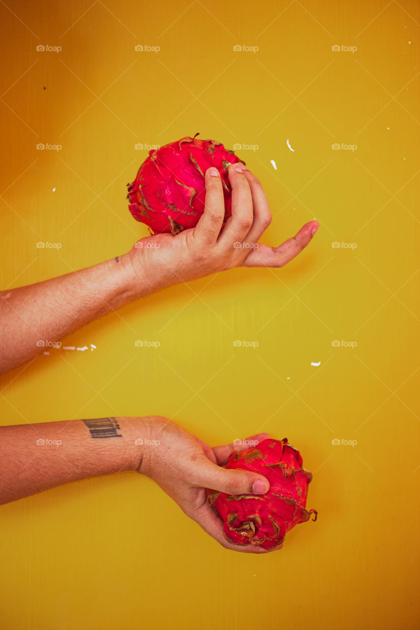 Tropical fruit held across a tellow backdrop