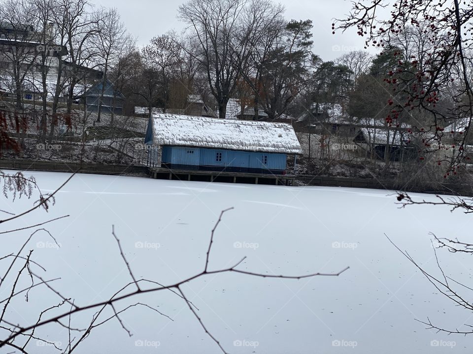 Winter, frozen lake and blue little house