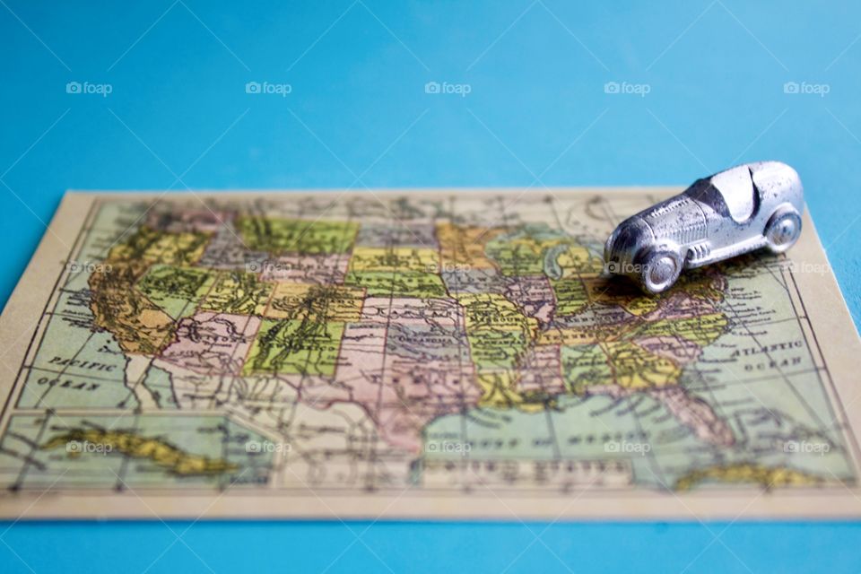 Miniature silver racer heading southwest on a miniature vintage map of the United States of America against a sky blue background