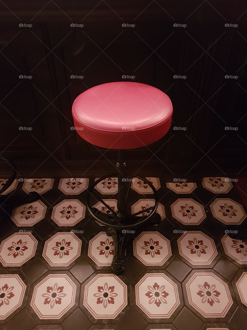 Red stool in a restaurant with decorated tiles floor in black, white and red