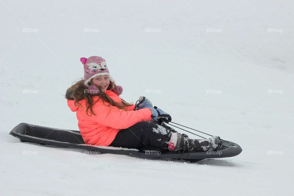 Smiling girl riding on sledge