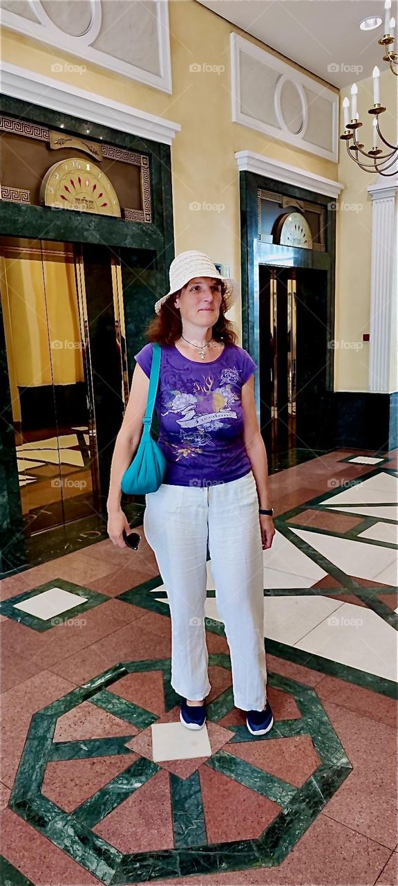 Today our globetrotting lady is in the foyer of “das Schloss”, “the Castle”, a popular multistory shopping mall in “Berlin”, capitol of Germany in the “Steglitz” neighborhood. 2024. Hypnotic Productions