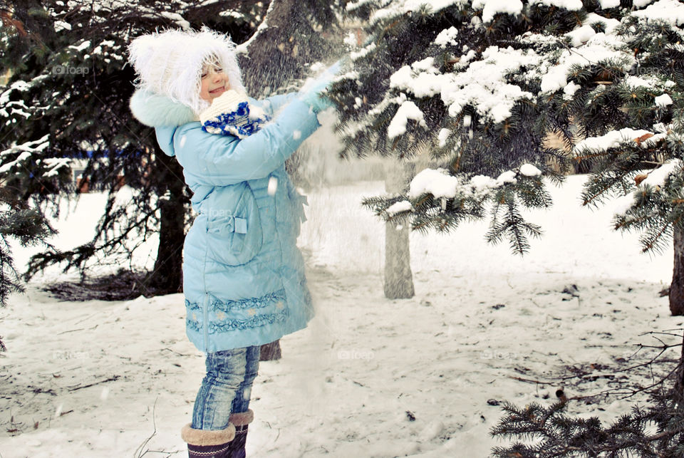 girl pulling a spruce brunch with snow