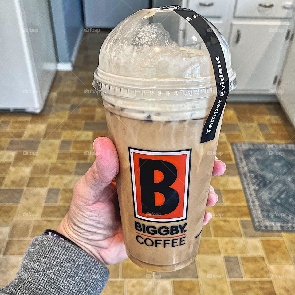 Woman drinking Biggby coffee, ordering DoorDash from home, ordering coffee from DoorDash, delicious iced coffee being held by woman