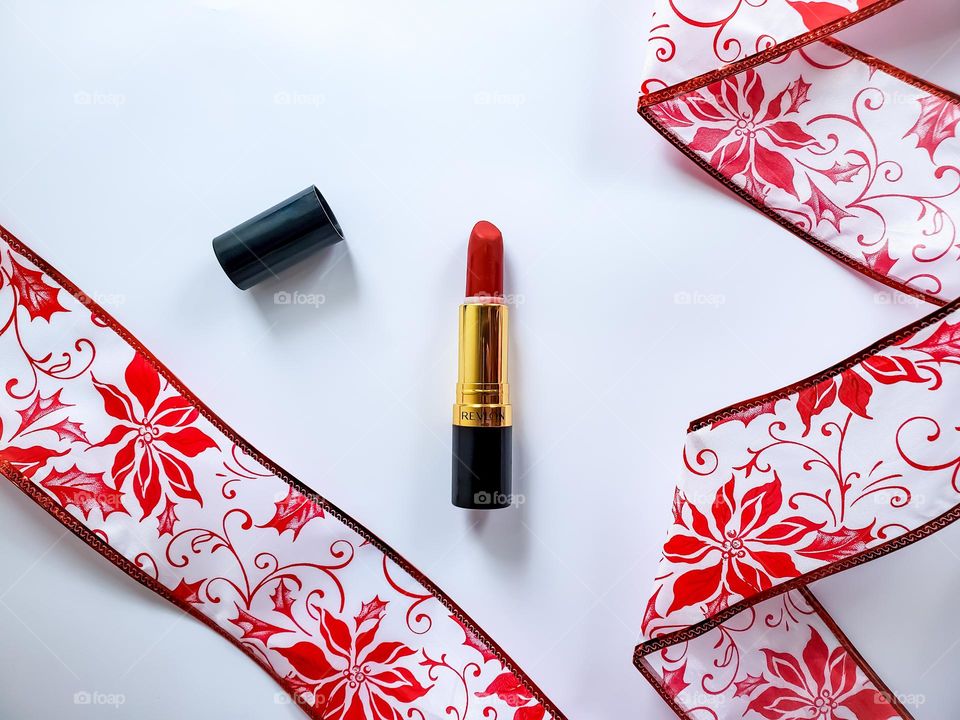 A vivacious red lipstick flatlay in a red and white holiday inspired theme.
