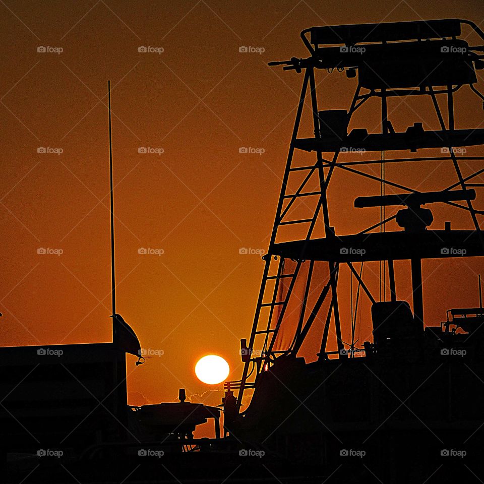 Sunrise, sunset and the moon - The orange sun rises over the silent fishing vessel 