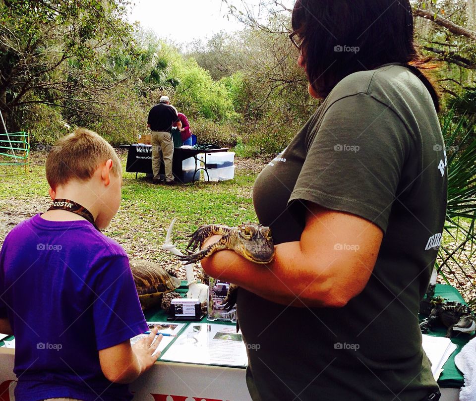Educating children about wildlife , introducing a baby alligator to a young boy.