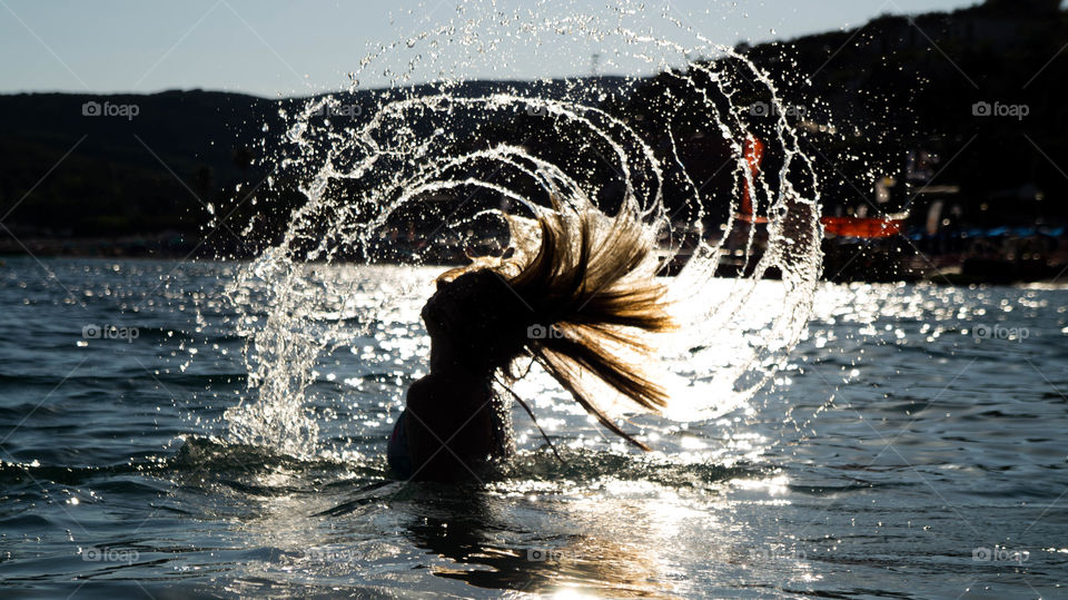 A girl pulling her head out of the water