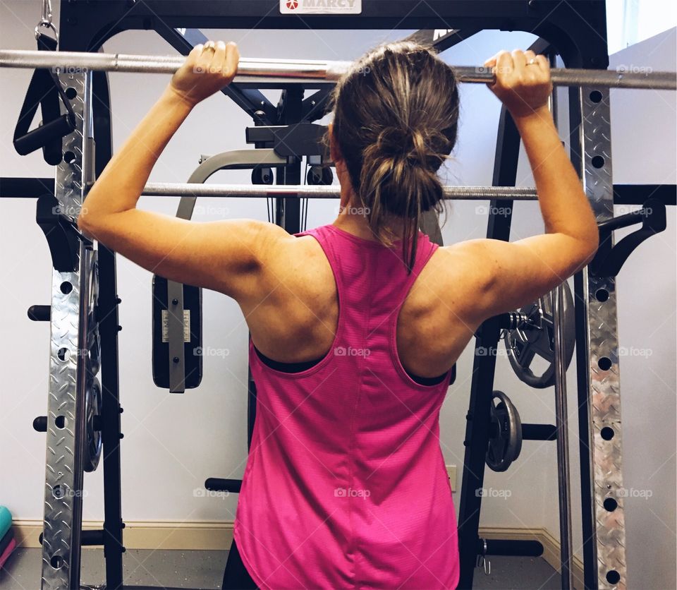 Woman with defined shoulders lifting weights. 