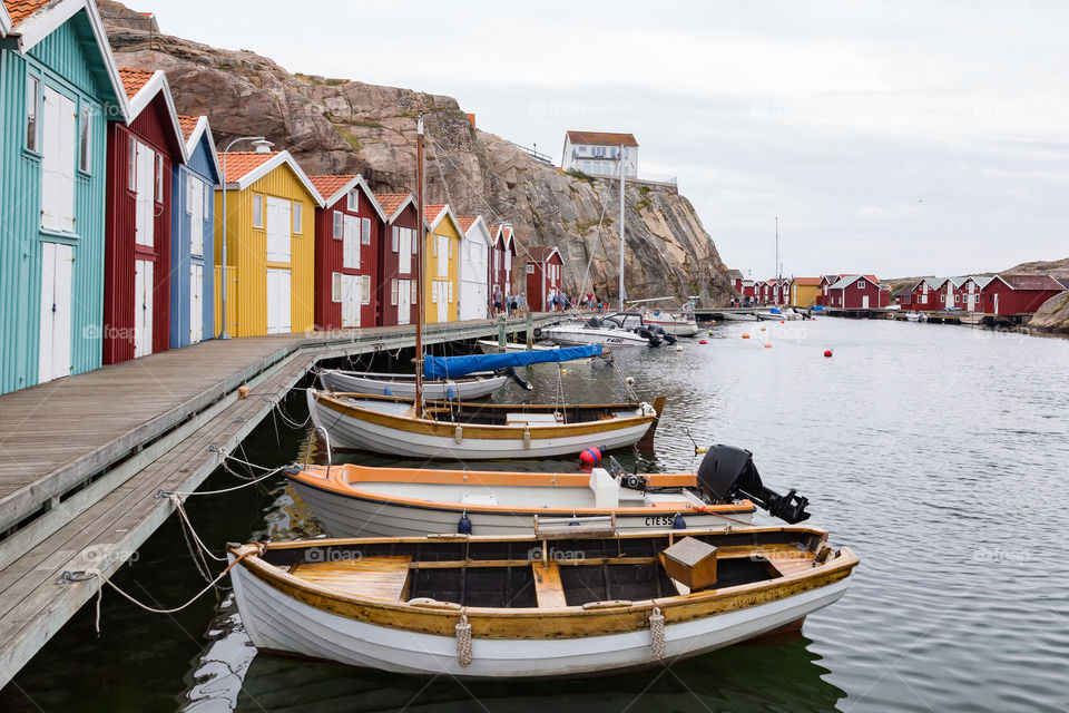 Colorful boathouses by the cliffs on the Swedish coastline, wooden pier with boats