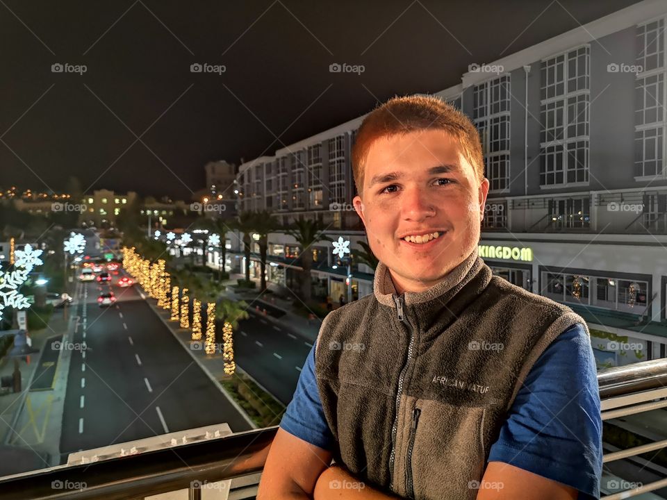 Teenager smiling broadly up high above City festive  night scene
