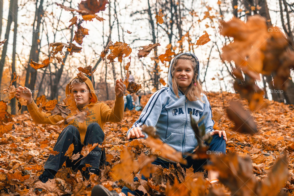 Kids playing with fall foliage in the park