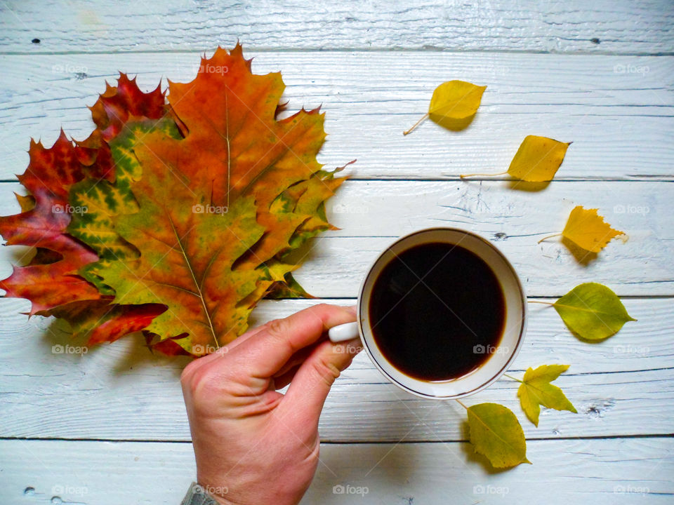 cup of coffee and a multi-colored autumn foliage