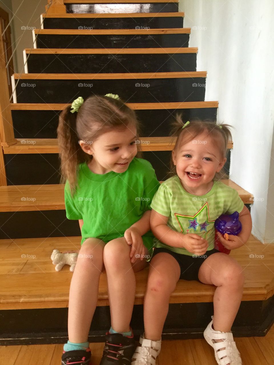 Happy sisters sitting on staircase