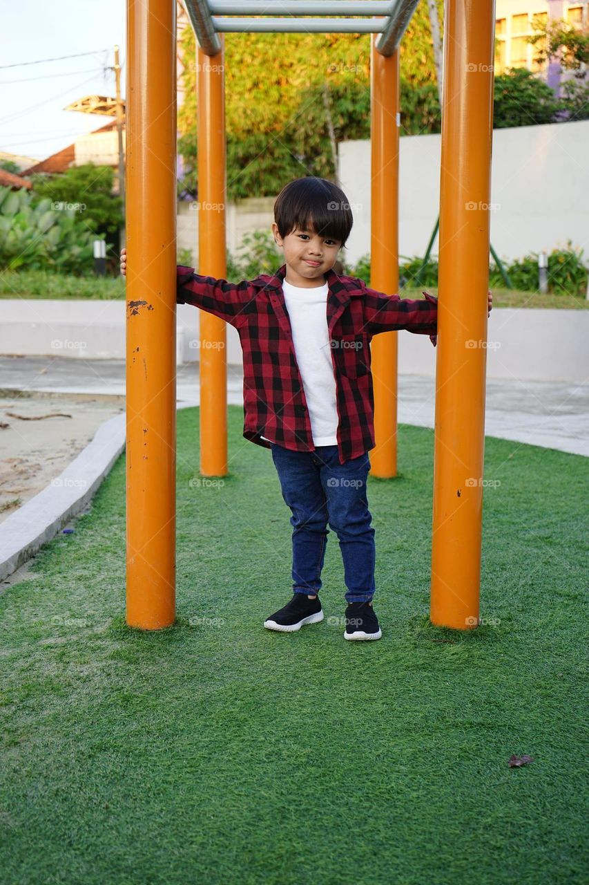 cute asian boy standing on a playground