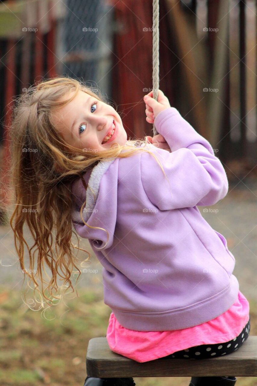 Smiling girl sitting on rope swing