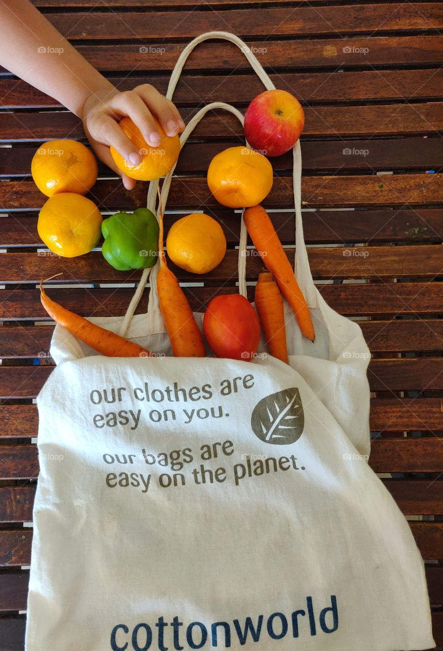 colorful fruits and vegetables out from a cotton tote bag on a wooden table